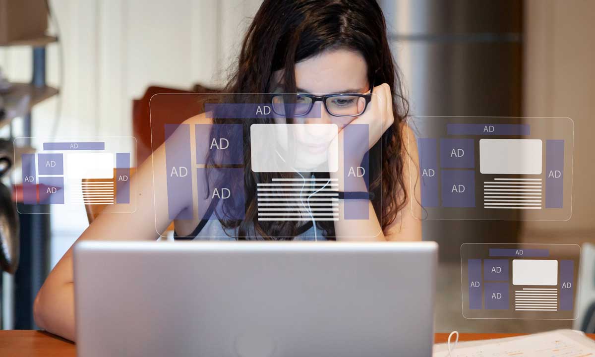 Woman frustrated by overwhelming display ads on computer screen, highlighting challenges of ad fatigue and ad blindness.